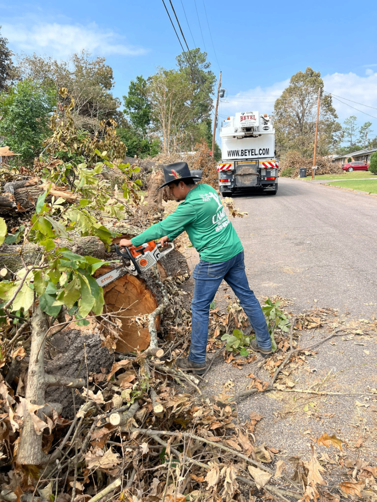 Emergency crew clearing a storm-fallen tree from a residential driveway at night